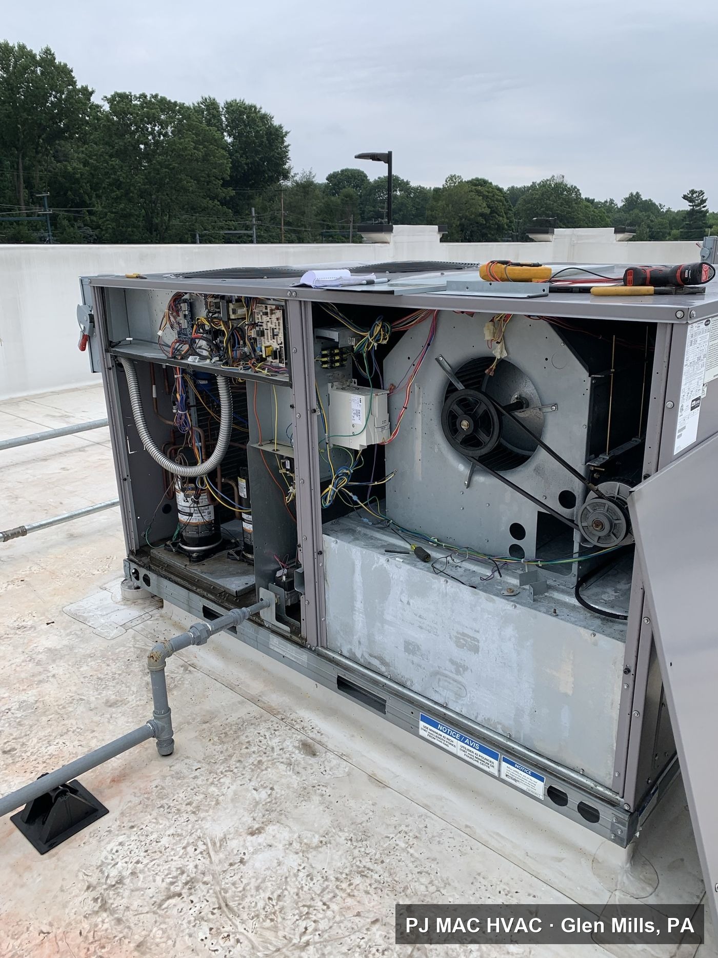 PJ MAC technician diagnosing a rooftop unit during maintenance