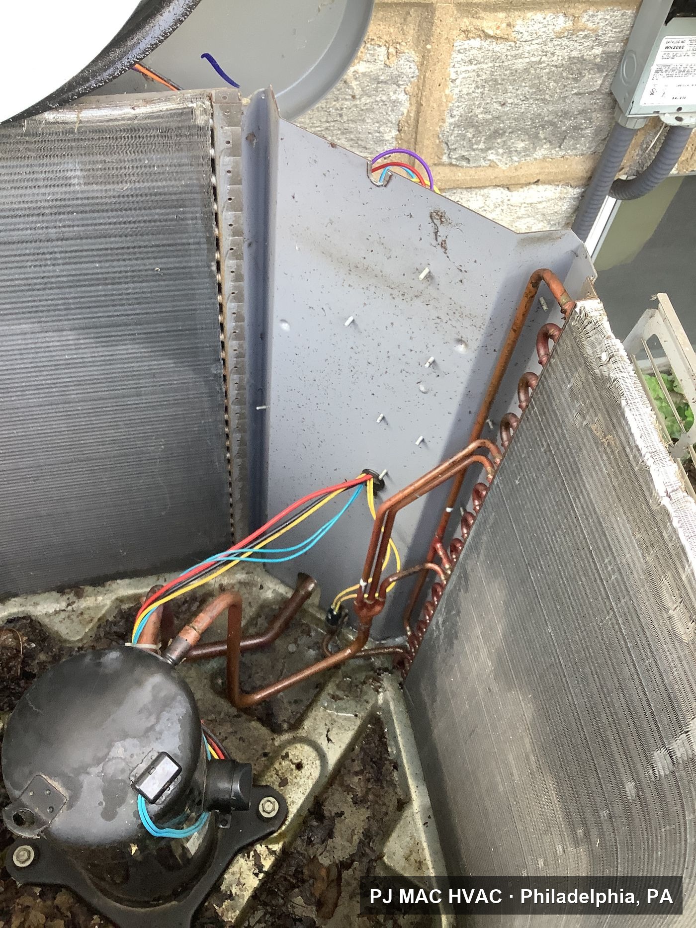 PJ MAC HVAC rebuilds an outdoor condenser, with the compressor and new copper refrigerant lines exposed.