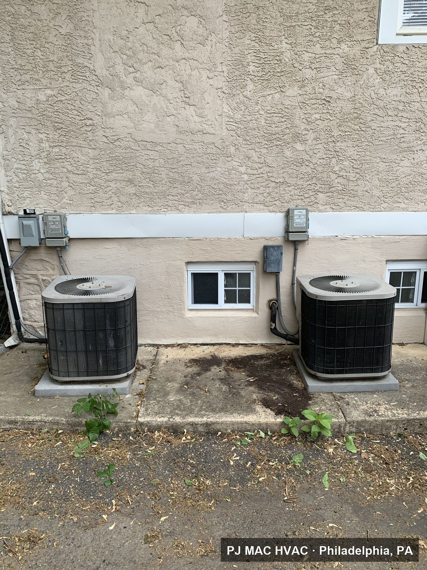 Two air conditioning condensers installed by PJ MAC HVAC along the side of a building.