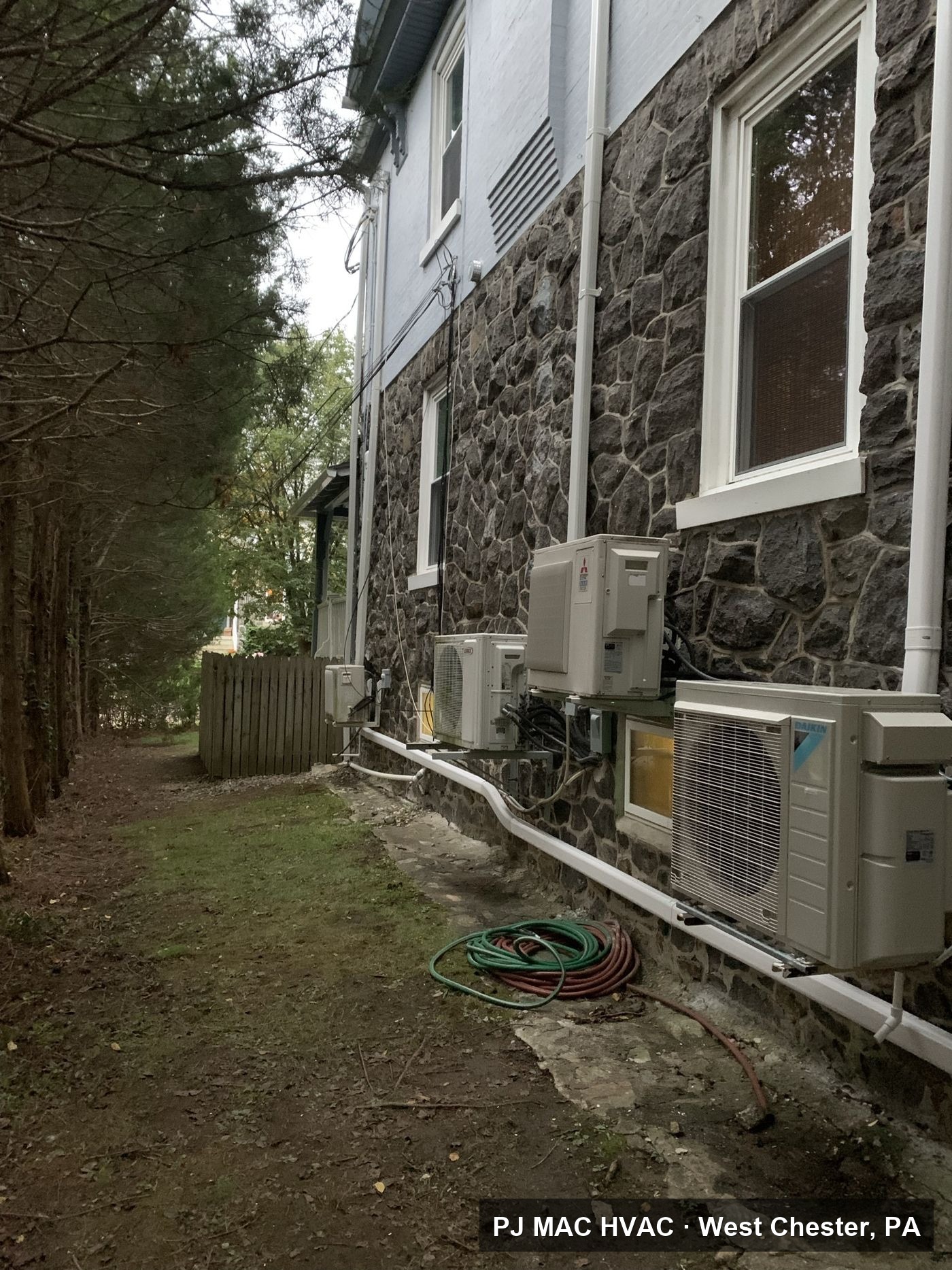 Multi-zone ductless mini-split condensers installed by PJ MAC HVAC along the stone exterior of a large home.