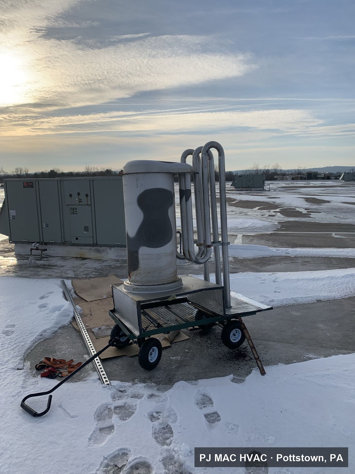 An old heat exchanger removed by PJ MAC HVAC, carted across a snowy commercial roof.