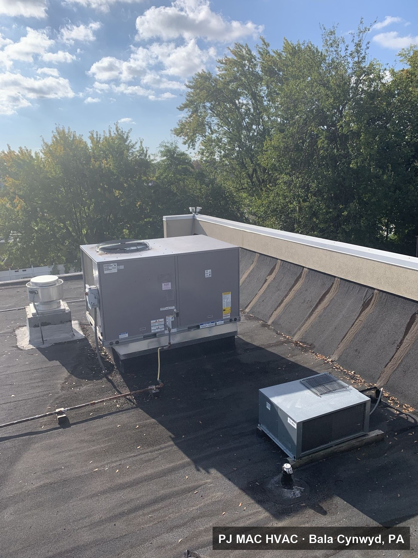 A curb-mounted rooftop packaged unit and condenser maintained by PJ MAC HVAC on a commercial building.