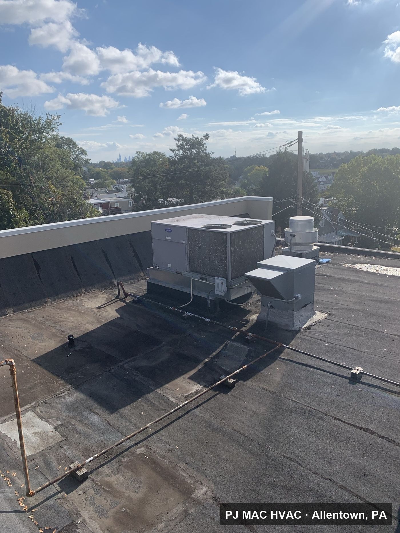 A commercial rooftop HVAC unit serviced by PJ MAC HVAC on a flat roof overlooking the Philadelphia area.