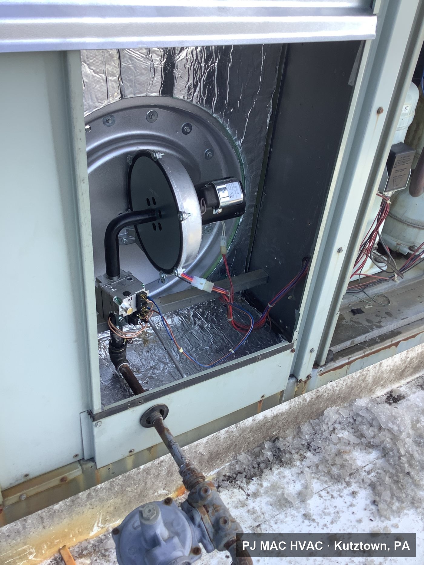 Inside the burner compartment of a commercial rooftop unit during a PJ MAC HVAC repair.